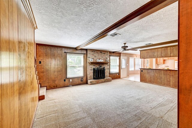 7907 Aleta Dr, Spring, TX 77379 - unfurnished living room featuring wood walls, ceiling fan, a textured ceiling, a fireplace, and stairway