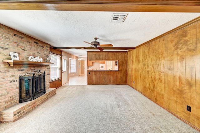 7907 Aleta Dr, Spring, TX 77379 - unfurnished living room featuring wooden walls, light carpet, a brick fireplace, a ceiling fan, and a textured ceiling