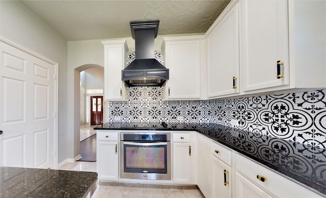 2506 Foxcrest Dr, Katy, TX 77494 - kitchen with oven, arched walkways, custom range hood, and white cabinetry