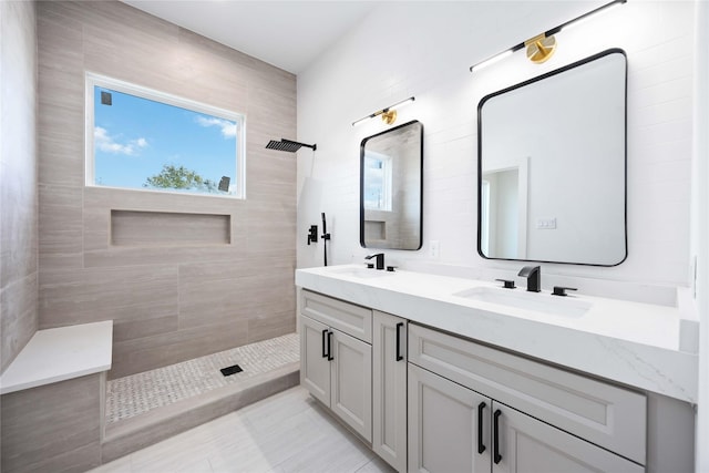 full bath featuring a tile shower and double vanity