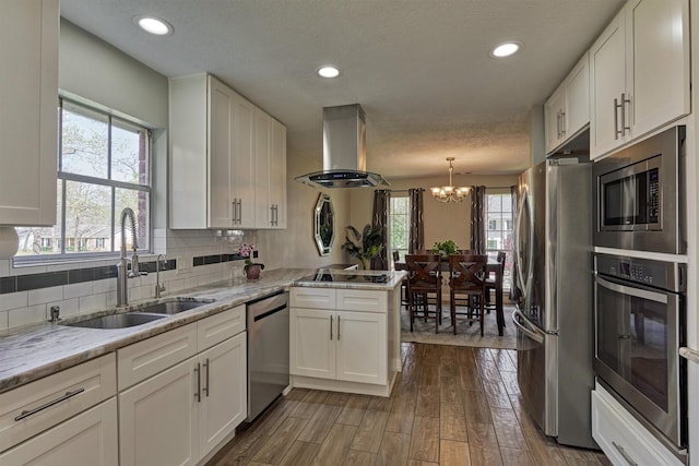 kitchen with appliances with stainless steel finishes, exhaust hood, a sink, white cabinets, and recessed lighting