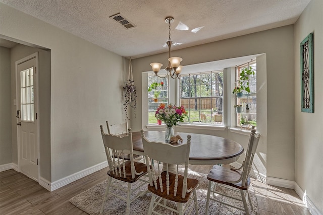 dining room with a chandelier, wood finished floors, baseboards, and a textured ceiling