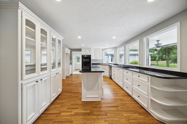 14303 Bonney Brier Dr, Houston, TX 77069 - kitchen with light wood finished floors, white cabinets, a center island, stainless steel appliances, and recessed lighting