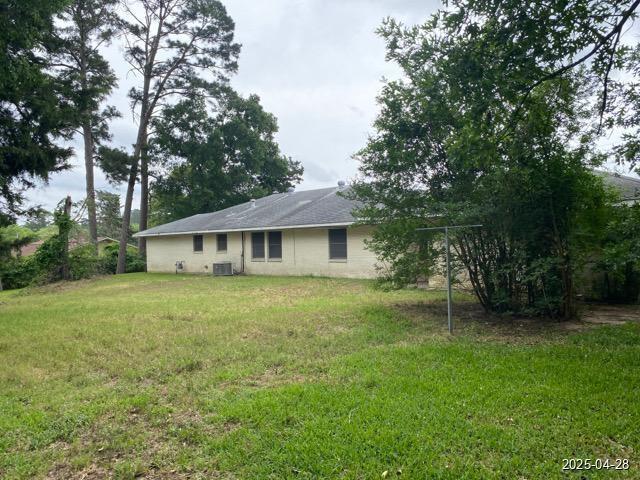 1912 18th St, Huntsville, TX 77340 - back of house with central air condition unit and a yard