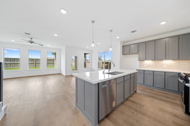 15198 Prairie Mill Dr, New Caney, TX 77357 - kitchen featuring dishwasher, gray cabinets, recessed lighting, open floor plan, and light wood-style floors