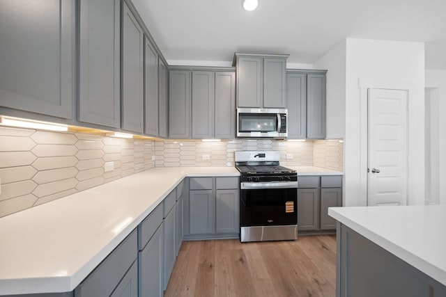 15198 Prairie Mill Dr, New Caney, TX 77357 - kitchen featuring stainless steel appliances, gray cabinets, light wood-style floors, and light countertops