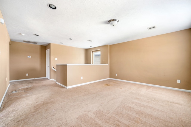 spare room featuring light carpet and baseboards