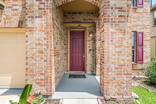 doorway to property with brick siding and a garage
