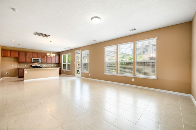 unfurnished living room featuring a chandelier, baseboards, and light tile patterned flooring