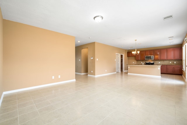 unfurnished living room featuring a chandelier and baseboards