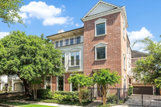 view of front of house with brick siding, a balcony, and fence