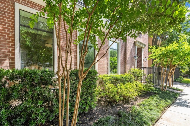 view of property exterior featuring brick siding and fence