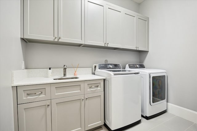 laundry area featuring separate washer and dryer, cabinet space, baseboards, and light tile patterned floors