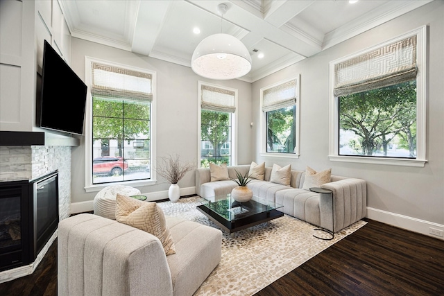 living area featuring dark wood-style flooring, coffered ceiling, baseboards, a stone fireplace, and crown molding
