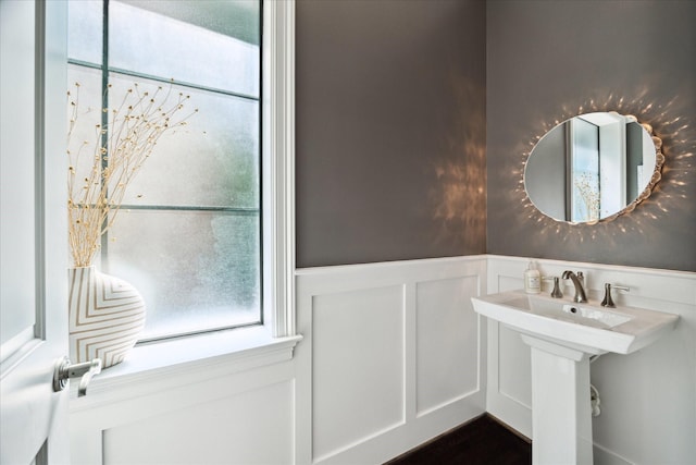 bathroom featuring wainscoting, a decorative wall, and a sink