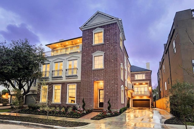 view of front of property featuring brick siding, a balcony, driveway, and an attached garage