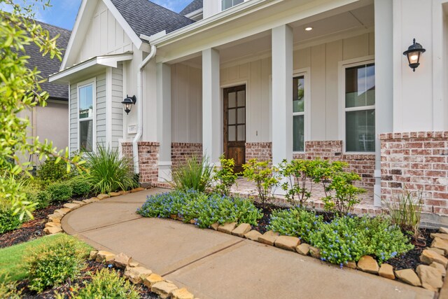 5357 Cherry Spring Dr, Spring, TX 77386 - doorway to property featuring brick siding, board and batten siding, roof with shingles, and a porch