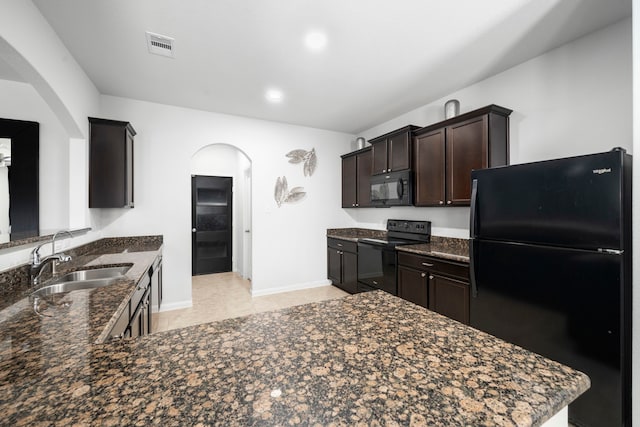 6263 El Turquesa Dr, Houston, TX 77048 - kitchen with black appliances, a sink, arched walkways, dark brown cabinets, and dark stone counters