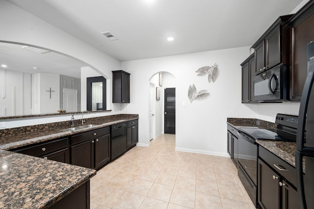 6263 El Turquesa Dr, Houston, TX 77048 - kitchen featuring black appliances, arched walkways, dark stone countertops, a sink, and light tile patterned floors