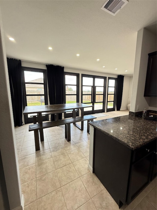6263 El Turquesa Dr, Houston, TX 77048 - kitchen featuring dark stone countertops, light tile patterned flooring, dark cabinetry, recessed lighting, and a peninsula