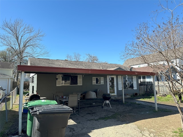 back of house featuring fence and a shingled roof