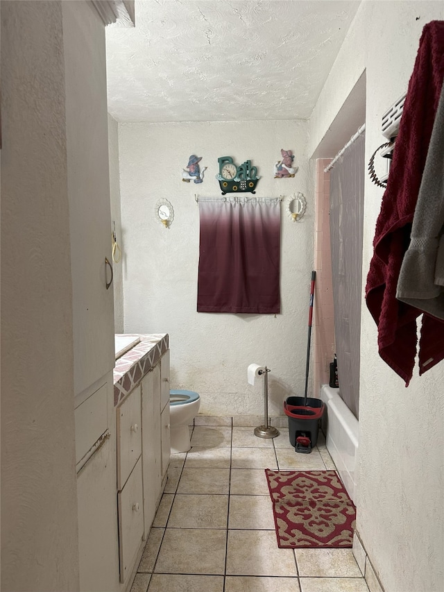full bath featuring a textured ceiling, toilet, a textured wall, tile patterned flooring, and vanity
