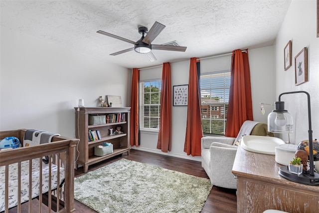 18406 Bristol Bay Ct, Humble, TX 77346 - bedroom with a textured ceiling, dark wood-type flooring, a ceiling fan, a crib, and baseboards