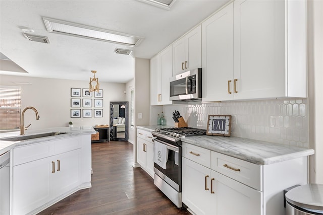 18406 Bristol Bay Ct, Humble, TX 77346 - kitchen with stainless steel appliances, a sink, dark wood-type flooring, backsplash, and white cabinets