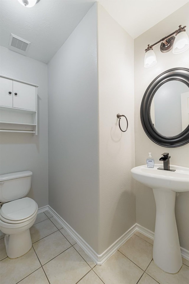 bathroom featuring tile patterned flooring, toilet, and baseboards