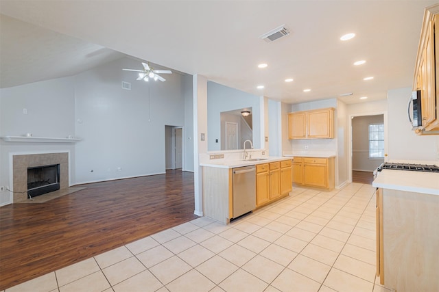 kitchen with stainless steel appliances, light brown cabinets, open floor plan, light tile patterned floors, and a ceiling fan