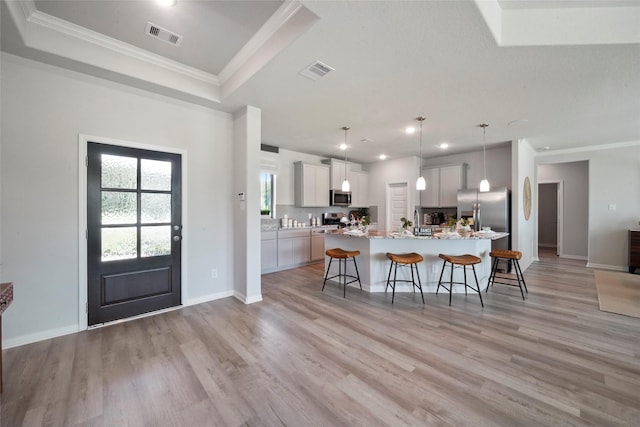 kitchen featuring stainless steel appliances, a breakfast bar, light wood-style flooring, a center island with sink, and recessed lighting