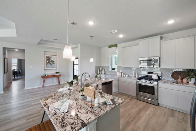 kitchen featuring appliances with stainless steel finishes, a sink, decorative backsplash, light wood-style flooring, and recessed lighting