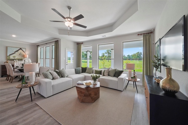 living area featuring light wood-style floors, plenty of natural light, and a ceiling fan