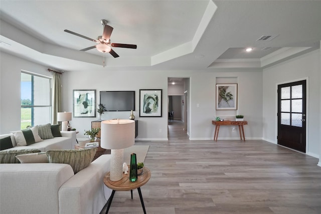 living room with a tray ceiling, ceiling fan, light wood-type flooring, baseboards, and recessed lighting