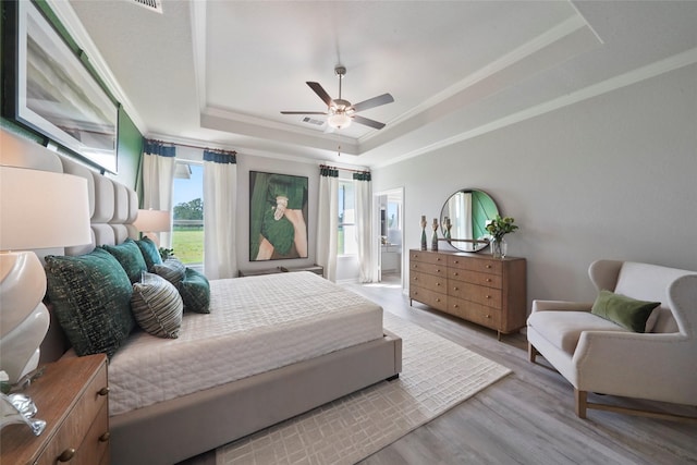 bedroom with a raised ceiling, wood finished floors, ornamental molding, and ceiling fan