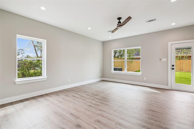 empty room featuring plenty of natural light, wood finished floors, ceiling fan, recessed lighting, and baseboards