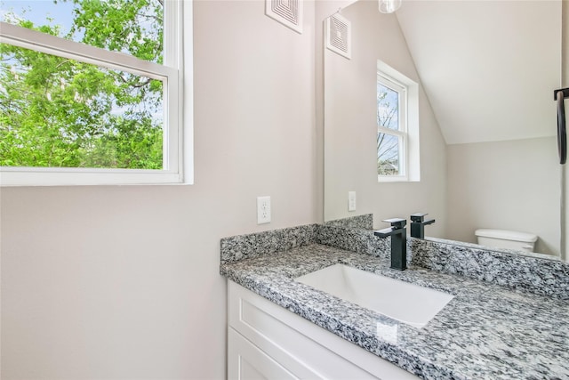 half bath featuring vaulted ceiling, toilet, and vanity