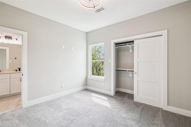 unfurnished bedroom with baseboards, light carpet, ensuite bathroom, and a closet