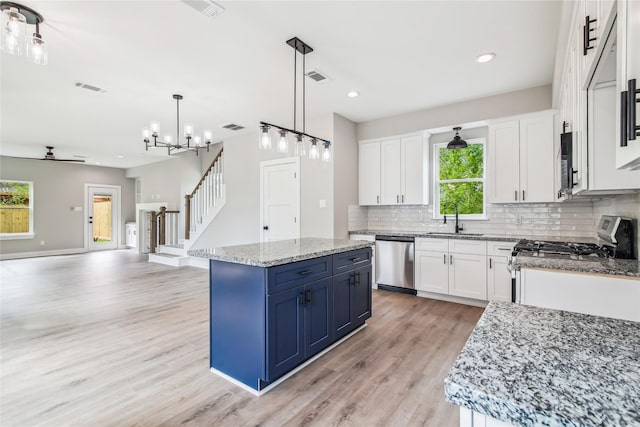 kitchen featuring stainless steel appliances, blue cabinets, tasteful backsplash, light wood-type flooring, and a center island
