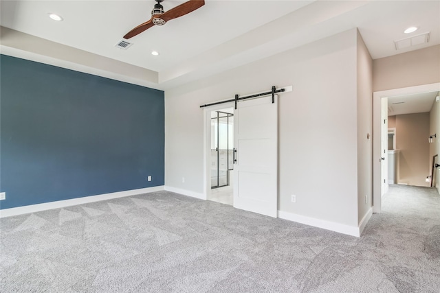 unfurnished bedroom with carpet, a barn door, baseboards, recessed lighting, and a ceiling fan