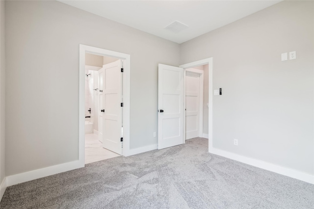unfurnished bedroom with carpet floors, baseboards, and connected bathroom