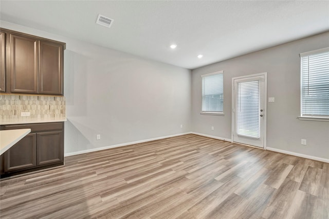 unfurnished living room with light wood-style flooring, plenty of natural light, recessed lighting, and baseboards
