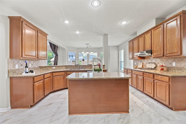 17406 Lonesome Dove Trl, Houston, TX 77095 - kitchen featuring under cabinet range hood, a sink, a peninsula, recessed lighting, and light marble finish flooring