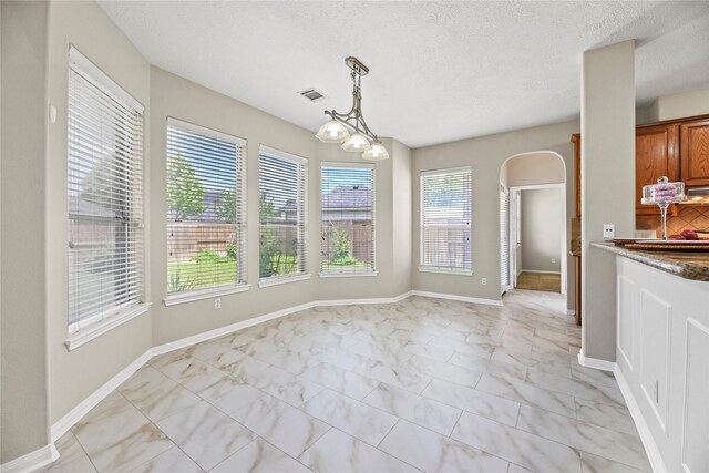 17406 Lonesome Dove Trl, Houston, TX 77095 - unfurnished dining area featuring arched walkways, light marble finish flooring, a textured ceiling, a chandelier, and baseboards