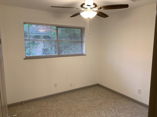 unfurnished room with ceiling fan and baseboards