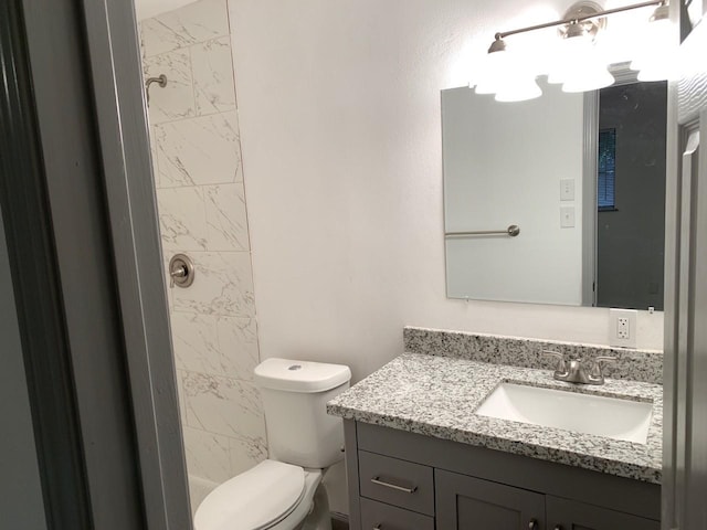 bathroom with vanity, toilet, and tiled shower