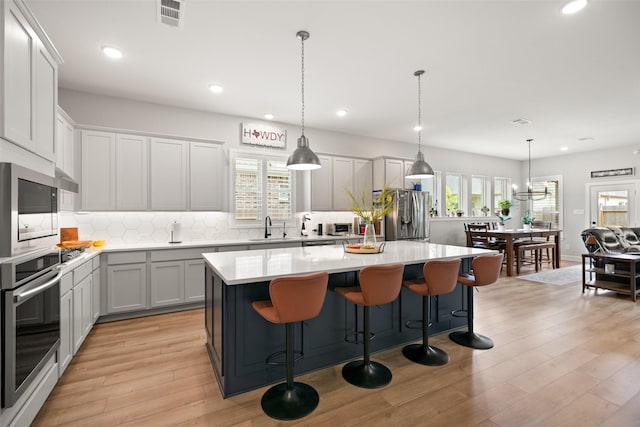29622 Cedar Elm Way, Tomball, TX 77375 - kitchen featuring stainless steel appliances, a kitchen island, backsplash, light countertops, and light wood-style flooring