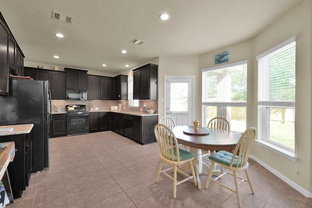 kitchen with black appliances, light tile patterned floors, recessed lighting, light stone countertops, and a sink