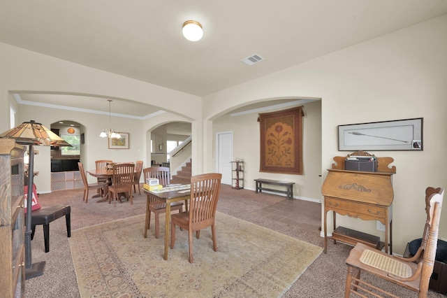 carpeted dining space featuring arched walkways, baseboards, and a chandelier