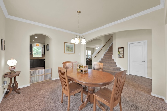 dining room featuring arched walkways, carpet flooring, a chandelier, crown molding, and stairs